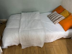 a bed with white sheets and orange pillows on a wooden floor at Pdmdecor House in Hunslet