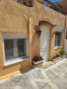 a building with two windows and a white door and flowers at Sunny Home II in Ermioni