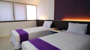 a hotel room with two beds and a window at YUTAKA INN Kalimas Ampel Surabaya in Surabaya