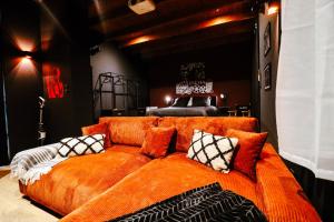 ein orangefarbenes Sofa mit Kissen darauf in einem Zimmer in der Unterkunft Cinéma privé - Movie Night Loft in La Force
