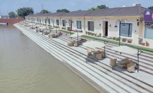 un bâtiment avec des tables et des parasols à côté de l'eau dans l'établissement Ayodhya haat Luxury Cottages, à Ayodhya