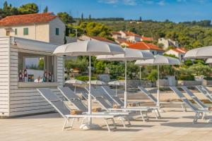 a row of lounge chairs and umbrellas on a deck at Grand Hotel View in Postira