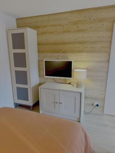 Un dormitorio con una cama y un televisor en una pared. en Les Duc(s) de l'Airelle, en Les Carroz d'Araches