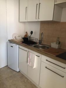 a kitchen with white cabinets and a sink at Grand Studio calme centre-ville in La Ferté-sous-Jouarre +4 photos