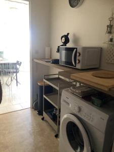 a kitchen with a microwave and a washing machine at Grand Studio calme centre-ville in La Ferté-sous-Jouarre +2 photos