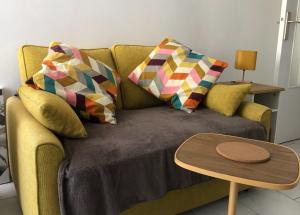 a couch with pillows and a table in a living room at Grand Studio calme centre-ville in La Ferté-sous-Jouarre