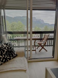 Una sala de estar con un sofá y un balcón con una mesa y sillas. en Les Duc(s) de l'Airelle, en Les Carroz d'Araches