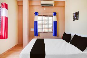 a bedroom with a bed with blue curtains and a window at Hotel O PALMS INN ELEGANT STAY in Bengaluru