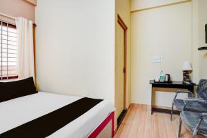a bedroom with a bed and a chair and a desk at Hotel O PALMS INN ELEGANT STAY in Bengaluru