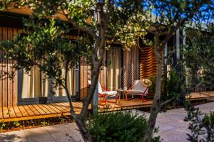 a house with a deck with a chair and a table at Waterman Beach Village in Supetar