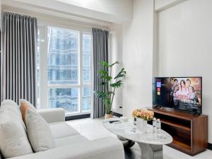a living room with a white couch and a tv at Modern 1BR w Exclusive Pool Access in Lapu Lapu City