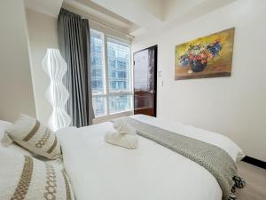 a white bedroom with two beds and a window at Modern 1BR w Exclusive Pool Access in Lapu Lapu City