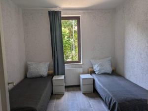 Dos camas en una habitación con ventana. en Ferienwohnung Coppenbrügge, en Coppenbrügge