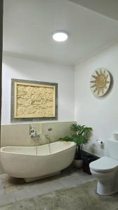 a white bathroom with a tub and a toilet at Villa Serenity in Lovina