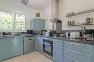 a large kitchen with blue cabinets and appliances at Charmante maison 6 à 8 pers PMR proche Lyon in Seyssuel