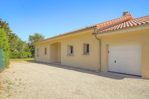 a house with two garage doors in a driveway at Charmante maison 6 à 8 pers PMR proche Lyon in Seyssuel