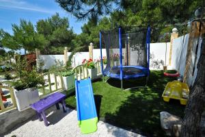 a playground with a swing in a yard at Secluded house with seawater pool in Milna