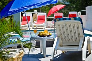 a table with a plate of fruit and a blue umbrella at Secluded house with seawater pool in Milna