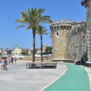 a bench in front of a castle with palm trees at Cascais Accomodations Estoril in Estoril
