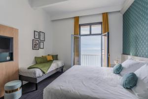 a bedroom with two beds and a window at Hôtel Morgat Le Grand Hôtel De La Mer in Crozon +45 photos