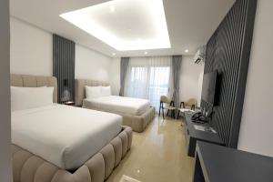 a hotel room with two beds and a couch at The Clover Hotel Angeles City in Angeles