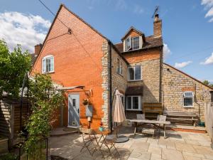 une maison en briques avec un patio et une table dans l'établissement Pass the Keys Traditional 3 Bed Cottage in Historic Village, à Stratford-upon-Avon