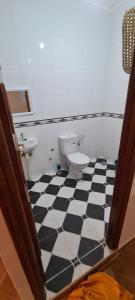 a bathroom with a toilet and a black and white checkered floor at Diki Beach Cosy place in Hammidane