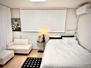 a bedroom with a white bed and a chair at Hi Seoul Daechi in Seoul