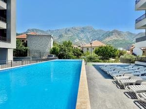 a swimming pool with chairs and mountains in the background at Apartment BAR M3A sea view in Bar