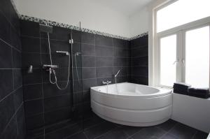 a bathroom with a white tub and a shower at SunnyBeach Luxury apartment in Zandvoort