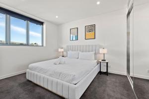 a white bedroom with a large bed and two windows at Big Two-Story with Private Elevator & Balconies in Sydney +33 photos