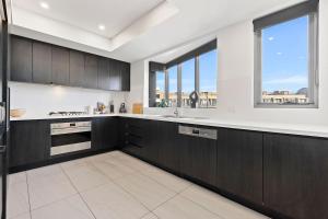a kitchen with black and white cabinets and windows at Big Two-Story with Private Elevator & Balconies in Sydney