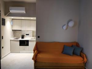 a living room with an orange couch and a kitchen at Aggeliki Apartment in Skiathos