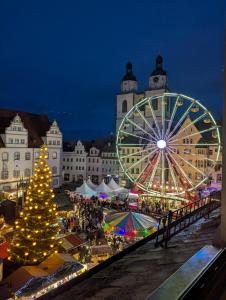 a christmas market with a christmas tree and a ferris wheel at Ferienwohnung Marktblick direkt am Wittenberger Weihnachtsmarkt in Lutherstadt Wittenberg