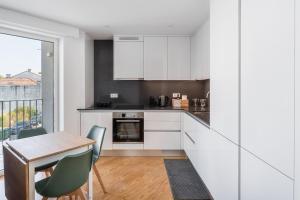 GervideにあるGuestReady - Relaxing Getaway Near Portoの白いキャビネットとテーブルと椅子のあるキッチン