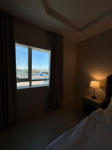 Dormitorio con ventana, cama y lámpara en diva suite نزل, en Hail