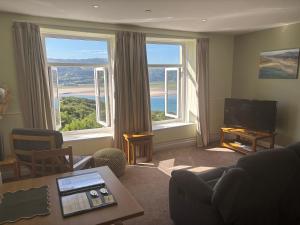 a living room with large windows with a view of the ocean at Bryn Melyn Apartments in Barmouth