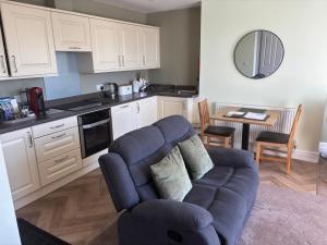 a living room with a blue couch and a kitchen at Bryn Melyn Apartments in Barmouth