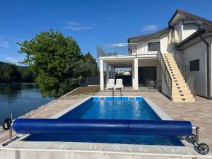 a swimming pool in front of a house at Apartmani na Uni Šarac in Otave