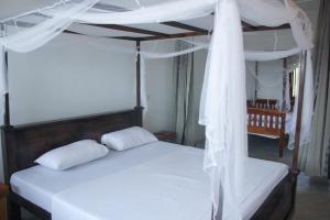a bedroom with a canopy bed with white sheets and pillows at Oceanview in Talpe