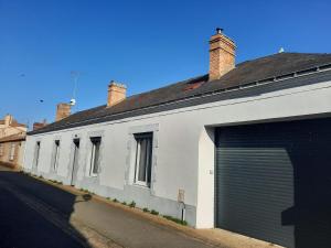 a white building with a garage on a street at La Moustache Bleue in Bouin