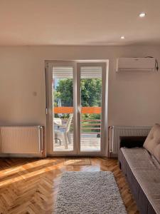 ein Wohnzimmer mit einer Couch und einer Glasschiebetür in der Unterkunft Apartmani Ana S in Vrnjačka Banja + 20 Fotos