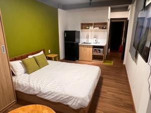 a bedroom with a white bed and a green wall at VACANCE APARTMENTs in Ho Chi Minh City