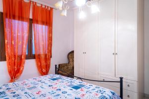 里奥内莱尔巴Appartamento Trilocale Cerboli的一间卧室，挂着橙色窗帘，里面有一张床和一个橱柜。