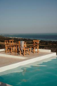 a picnic table and chairs next to a swimming pool at Ghar El Melh Outdoors in Raʼs al Jabal +29 photos
