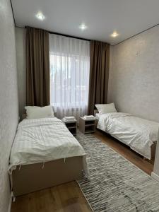 a bedroom with two beds and a window at Comfort Altyn-Emel in Kalīnīno