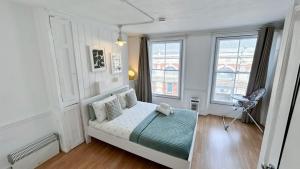 a small bedroom with a bed and two windows at Stylish 2-Bedroom Flat in Barbican Centre near Farringdon with Rooftop Terrace in London