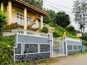 a house with a white fence in front of it at Grymsby Holiday Bungalow in Nuwara Eliya