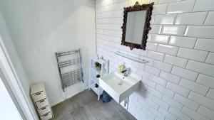 a white bathroom with a sink and a mirror at Stylish 2-Bedroom Flat in Barbican Centre near Farringdon with Rooftop Terrace in London