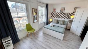 a small room with a bed and a chair and a window at Stylish 2-Bedroom Flat in Barbican Centre near Farringdon with Rooftop Terrace in London